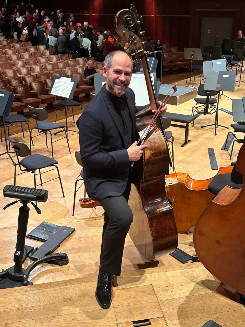 José Vilaplana smiling with his double bass on the stage of a concert hall